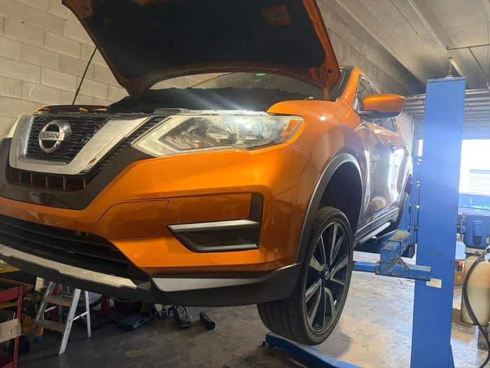 Orange Nissan Rogue with hood open for service at Fray Automotive